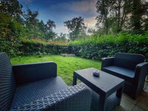 a patio with two chairs and a table and a lawn at Studio moderne St Germain les Corbeil - jacuzzi privatif in Saint-Germain-lès-Corbeil