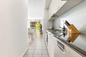 A Cozy & Modern Studio Right Next to Darling Harbour في سيدني: مطبخ أبيض مع حوض ومكتب