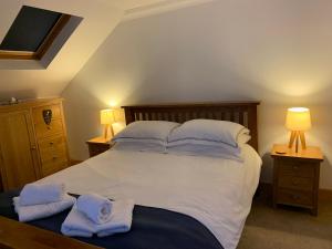 een slaapkamer met een groot bed en handdoeken bij Cameron Cottage in Inverkip