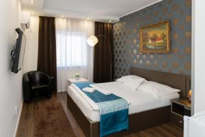 ein Hotelzimmer mit einem Bett und einem Stuhl in der Unterkunft Titan Centrum Apartman in Nyíregyháza