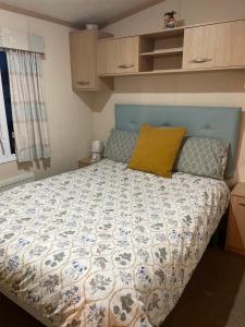 a bedroom with a bed with a blue and white comforter at Rockley Park- Turlin Valley 36 in Lytchett Minster