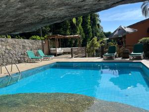 a swimming pool with two chairs and a table at Yannai Chalé Praia in Ilhabela