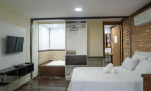 1 dormitorio con 1 cama y baño con bañera en Yannai Chalé Praia en Ilhabela