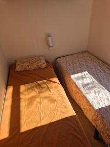 dwa łóżka w małym pokoju z promieniami słońca w obiekcie Paisible camping les 7 fonds w mieście Agde