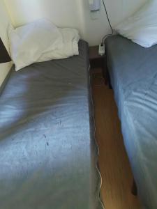 Ce lit se trouve dans une petite chambre dotée d'un couvre-lit. dans l'établissement Paisible camping les 7 fonds, à Agde