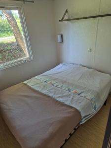 Łóżko w małym pokoju z oknem w obiekcie Paisible camping les 7 fonds w mieście Agde