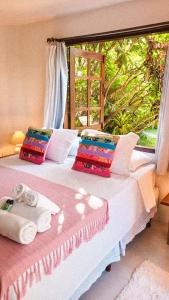ein Bett mit zwei Kissen und ein Fenster in einem Zimmer in der Unterkunft Pousada Flor Do Mar in Caraíva