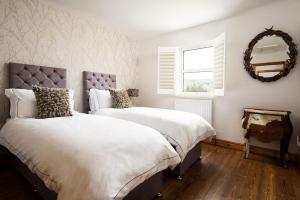 a bedroom with two beds and a mirror at The Old School in Edlingham