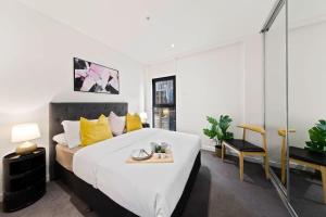 a bedroom with a large bed with yellow pillows at A Modern & Spacious 2BR Apt City Views Southbank in Melbourne