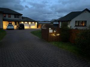 a driveway in front of a house with a fence at The Grove Cabin in Fort William