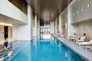 une piscine dans un bâtiment avec des personnes assises autour de lui dans l'établissement A Lux & Modern Apt Next to Southern Cross Station, à Melbourne