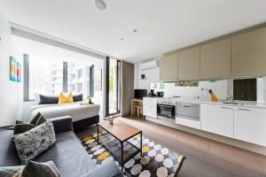 ein Wohnzimmer mit einem Sofa und einer Küche in der Unterkunft A Stylish CBD Studio Right Next to Southern Cross in Melbourne
