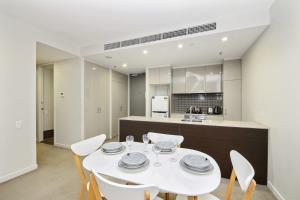 une salle à manger avec une table et des chaises blanches dans l'établissement A Comfy Albert Park Apt Next to Grand Prix Circuit, à Melbourne