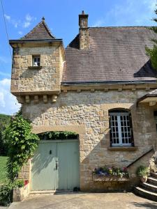 サン・シプリアンにあるLa périgourdine et son spaの緑色のガレージドアのある古い石造りの建物