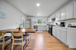 una cucina con armadi bianchi e tavolo e sedie in legno di Midtown Modern Cottage a Tyler