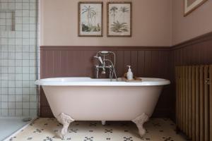 a white tub in a bathroom with two pictures on the wall at The Old Rectory in Brampton