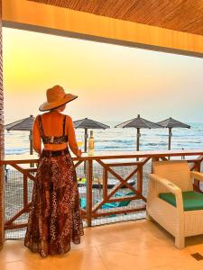 Una donna con un cappello in piedi a un tavolo che si affaccia sull'oceano di fantástico, paraíso, mar, atardeceres, playa, Paz a San Silvestre