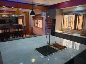 a kitchen with a sink and a living room at An Entire Rare Stylish 5-Bedroom Bungalow in Akure