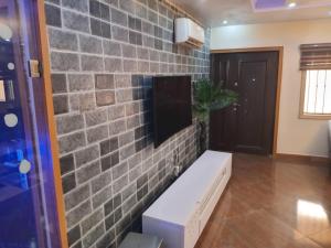 una pared de ladrillo con un banco y una TV en ella en An Entire Rare Stylish 5-Bedroom Bungalow, en Akure