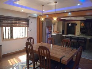 a kitchen and dining room with a wooden table and chairs at An Entire Rare Stylish 5-Bedroom Bungalow in Akure