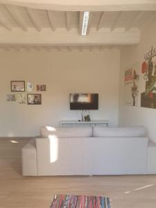 a white living room with a white couch and a tv at Come a casa vostra in Lucca