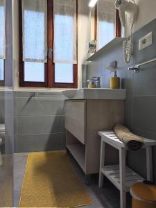 ein Badezimmer mit einem Waschbecken und einer Theke mit einem Stuhl in der Unterkunft La Casina Sondrio Valtellina in Sondrio
