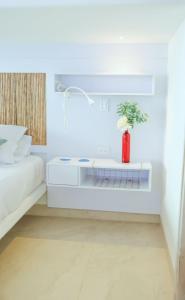una camera bianca con un letto e un vaso rosso di fantástico, paraíso, mar, atardeceres, playa, Paz a San Silvestre
