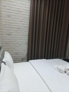 a bed with white sheets and pillows in a room at GOLDEN TRIP Hotel in Yunusobod