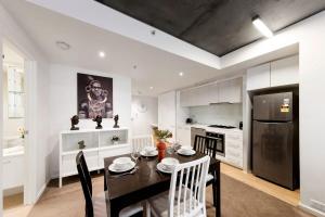 cocina con mesa negra y armarios blancos en A Cozy Apt Near Grand Prix Circuit FREE Parking en Melbourne