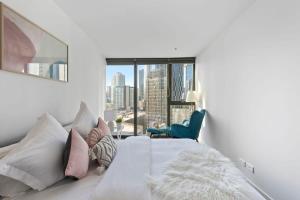 a bedroom with a white bed with a large window at A Stylish & Cozy Apt Near Crown with City Views in Melbourne