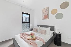 a white bedroom with a bed with a tray with flowers on it at An Amazing 2BR Apt with City Views in Southbank in Melbourne