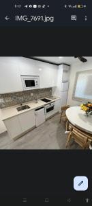 a kitchen with white cabinets and a table and a dining room at Casa la florida in Puebla de Sanabria