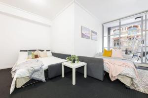 a bedroom with two beds and a table at A Comfy Studio for 6 Next to Darling Harbour in Sydney +15 photos