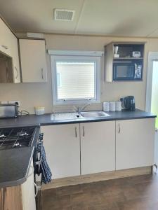 a kitchen with white cabinets and a sink and a window at Three bedroom holiday home in Whitstable