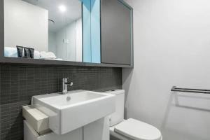 a bathroom with a sink and a toilet and a mirror at A 3BR Apt Next to Melbourne Zoo FREE Parking in Melbourne
