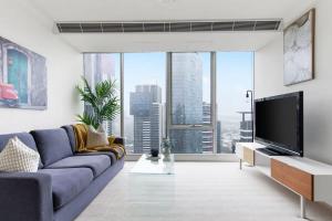 sala de estar con sofá azul y TV de pantalla plana en Comfy & Stylish 2BR Apt Next to Crown City Views en Melbourne