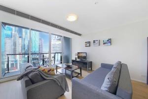 een woonkamer met een bank, een tv en een groot raam bij A Stylish 2BR Apt Next to Crown with FREE Parking in Melbourne