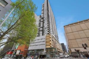 a tall building on a city street with buildings at Comfy CBD Apt in QV with City Views FREE Parking in Melbourne +14 photos
