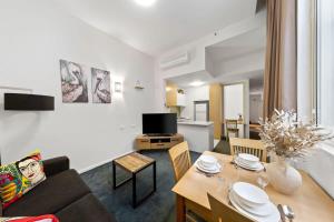 a living room with a couch and a table with chairs at A Chic Apartment on Bourke St Near Chinatown in Melbourne