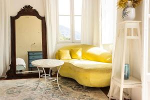 sala de estar con sofá amarillo y espejo en Lovenest: romantic apartment overlooking the lake, en Oggebbio
