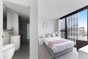 a white bedroom with a bed and a bathroom at A Chic 2BR Apt Near Melbourne CBD w FREE Parking in Melbourne