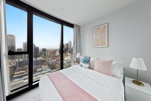 a bedroom with a white bed and a large window at A Chic 2BR Apt Near Melbourne CBD w FREE Parking in Melbourne