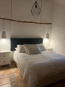 Finca El Sueño Andaluz في فيلانويفا دي لا كونسيبسيون: غرفة نوم بسرير ابيض كبير ومصباحين