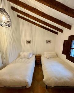 Finca El Sueño Andaluz في فيلانويفا دي لا كونسيبسيون: سريرين في غرفة ذات أغطية بيضاء