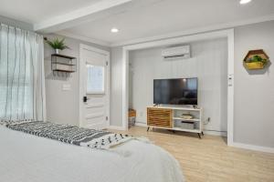 a white bedroom with a tv and a bed at Downtown Studio 1 at Beer Ranch Project Inn in Wimberley