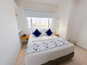 圣安德烈斯Hotel Grand Caribe的一间卧室，配有一张带蓝色枕头的床和一扇窗户