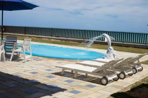 a fountain in a pool with a bench and a table at Pousada Doutora Lindalva in Maragogi