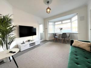 een woonkamer met een groene bank en een tv bij ArtLounge-2 bed garden Free parking in Enfield Lock