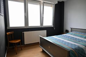 Schlafzimmer mit einem Bett, einem Stuhl und Fenstern in der Unterkunft Chez Maïse - CR CONCIERGERIE in Dunkerque
