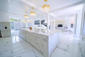 a white kitchen with a marble counter top and chandeliers at El AMO LAKEVIEW VILLA in Entebbe